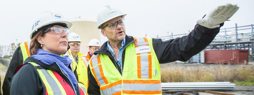 Two people wearing safety vests, glasses and hard hats