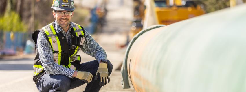 Smiling man knees beside gas pipeline
