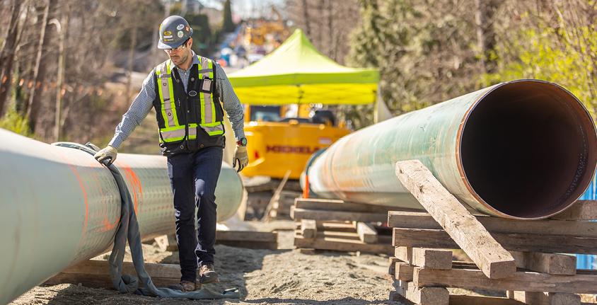Man walks alongside a pipe on a job site