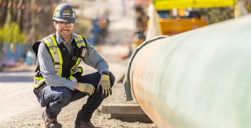 Smiling man knees beside gas pipeline