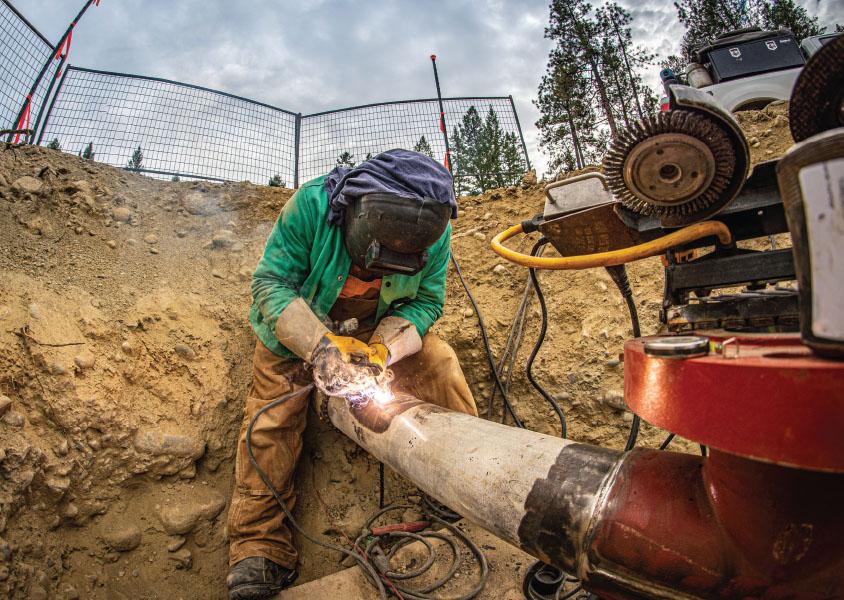 Worker welds a pipeline in a trench