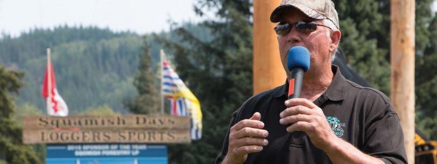 Man holding microphone in front of Squamish days sign