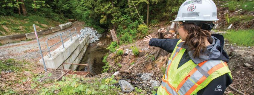 Woman in hard hat looks over newly installed creek crossing