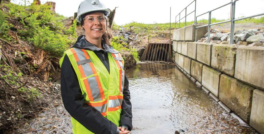 Woman smiles standing in front of a water culvert