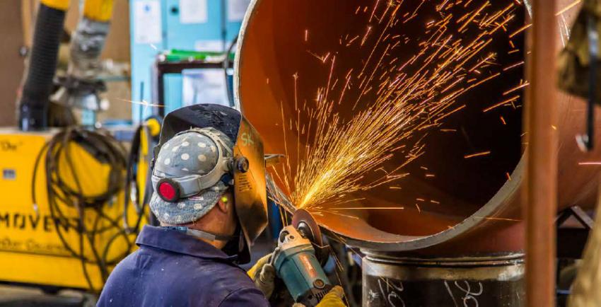 Welder works on pipe with sparks flying