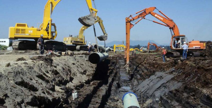 Two construction machines work along a pipeline trench