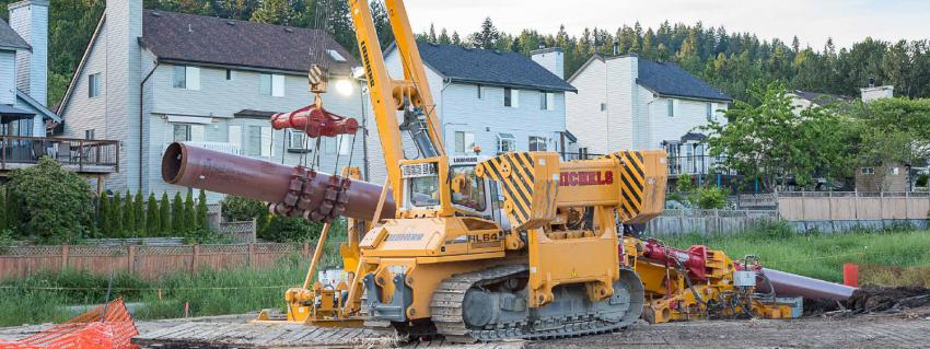 Construction machine hauls large piece of pipe