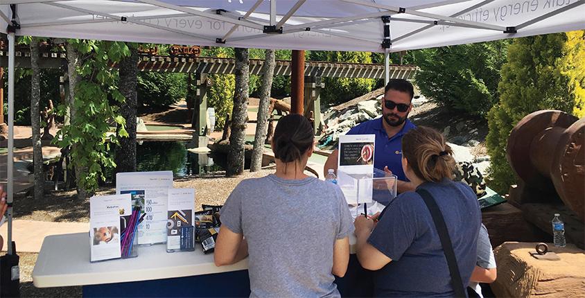 Two people at a FortisBC tent talk to a Street Team member