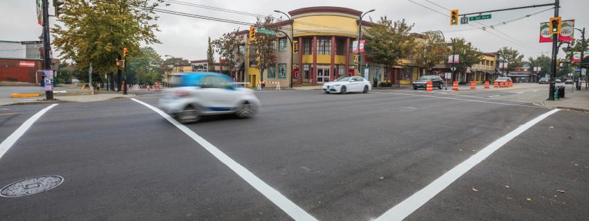 Cars drive through an intersection at Commercial Drive and East 1st Avenue