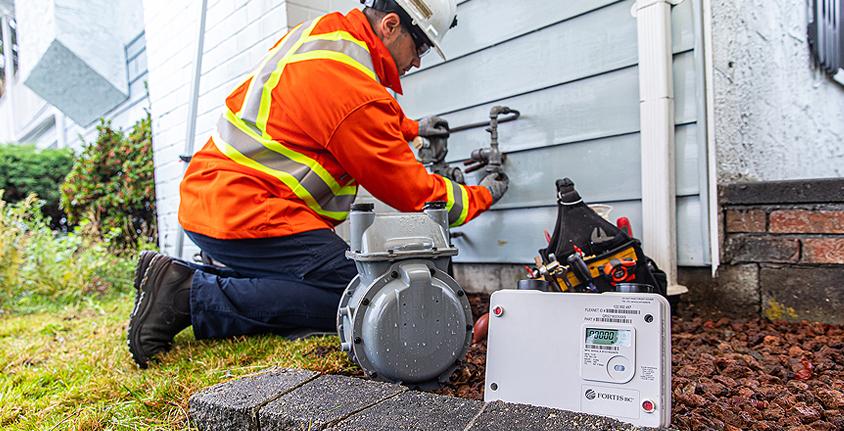 A worker replaces an existing FortisBC meter with an advanced gas meter