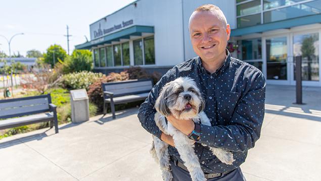 Man holding a dog smiles at the camera