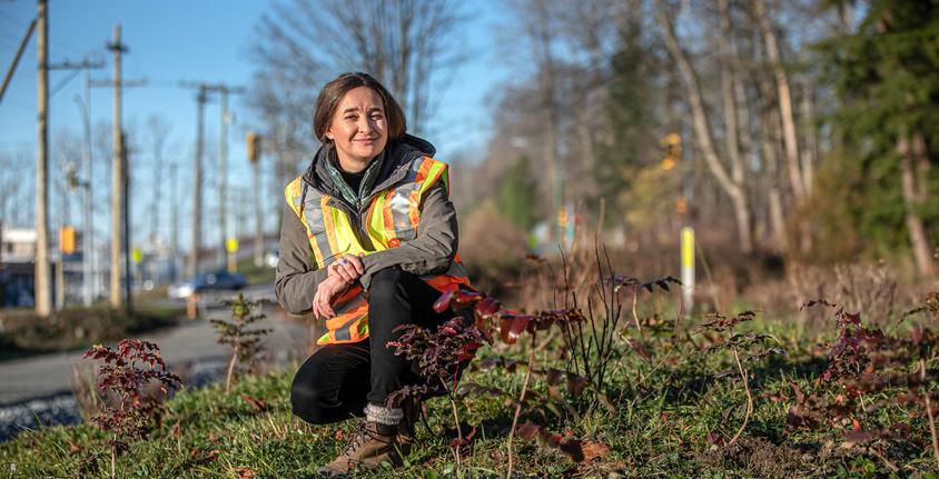 Woman kneels beside pollinator garden