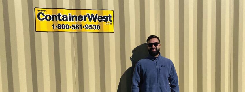 Man stands beside Container West sign
