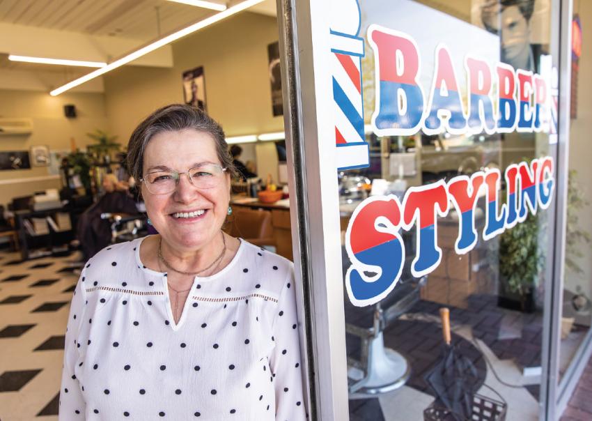 Smiling woman stands at the door of a barber shop