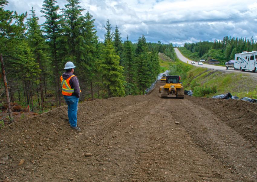 Worker stands along cleared right of way beside a highway for the Inland Gas Upgrades project