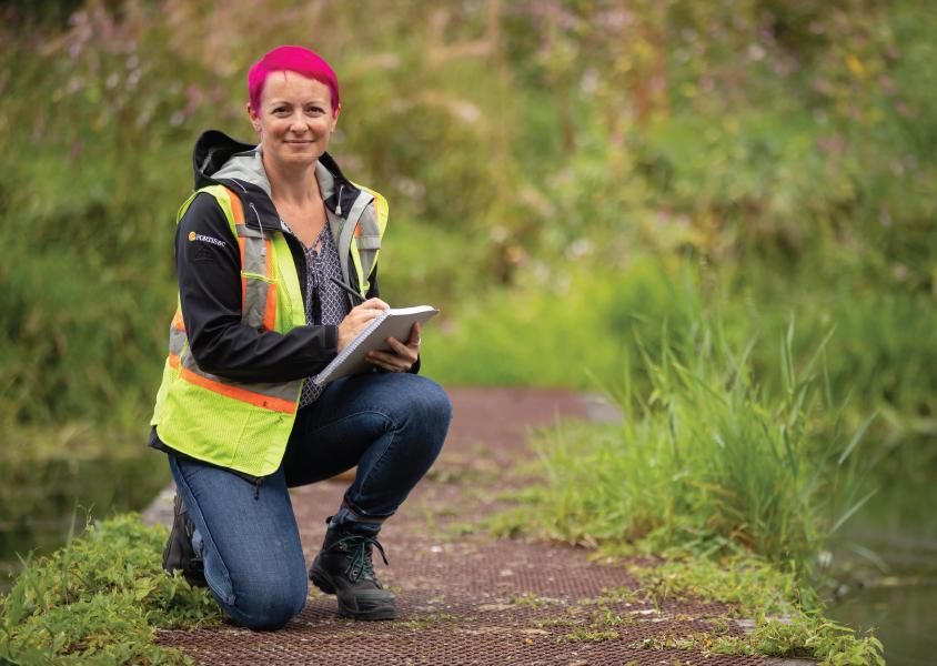 Caroline Astley kneels along a trail in Burnaby Lake park