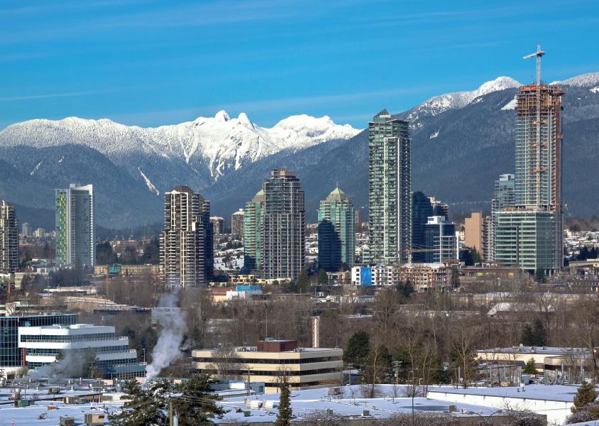 Burnaby skyline with blue sky and snow capped mountains in the background