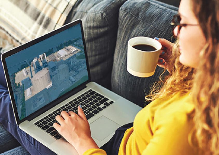 Woman lies on a couch with a coffee in her hand and a laptop on her lap, screen shows Tilbury LNG proposal