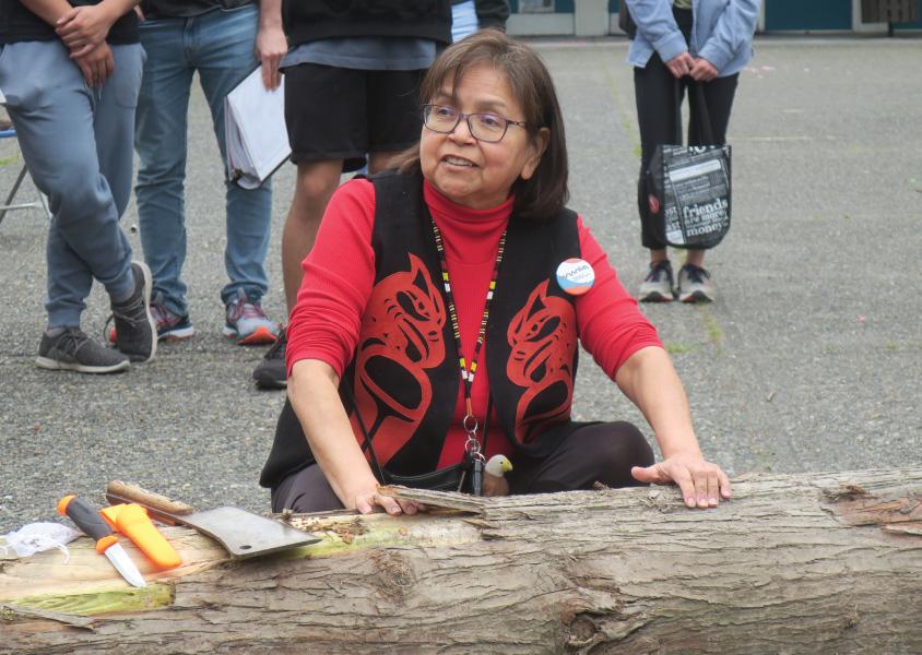 Elder Alice Guss with her hands on a cedar log