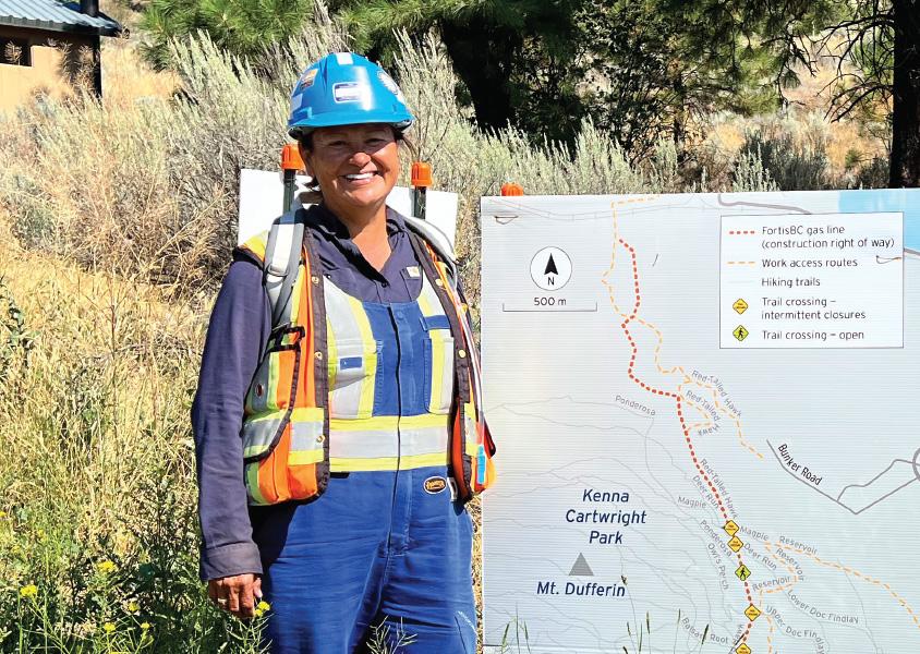 Vi Antione stands in front of a trail map at Kenna Cartwright park