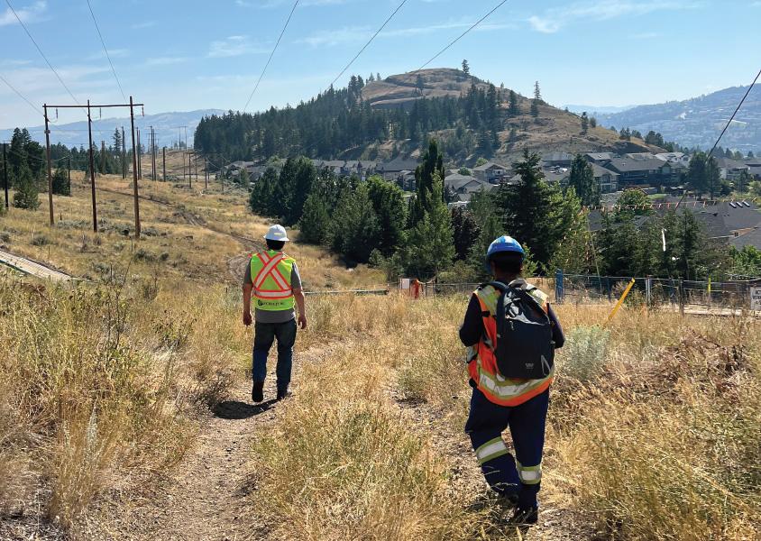 Two workers walk down a trail along a power line right of way in Kenna Cartwright Park