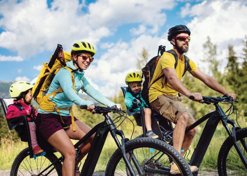 A family ride bikes on a trail on a sunny day