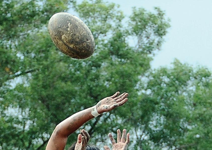 Hands reaching for a rugby ball