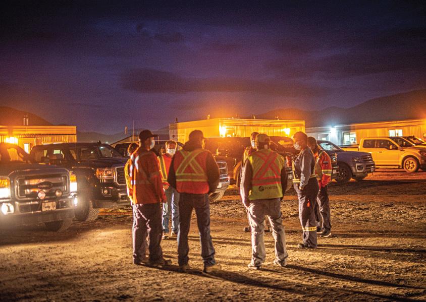Workers standing in a circle at a worksite at sunrise
