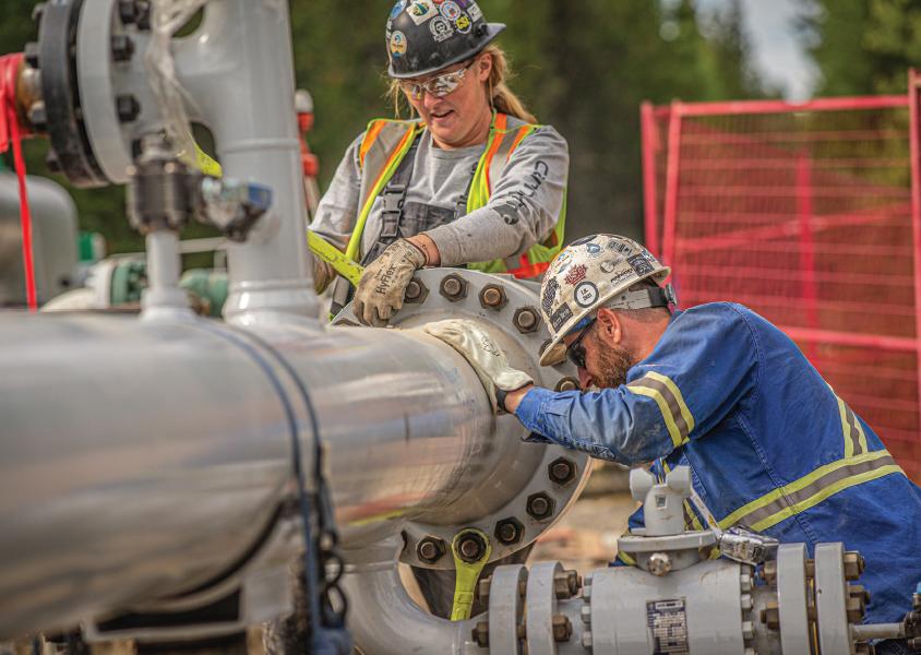 Two FortisBC employees work on a pipe on the IGU project