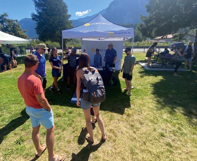 People gathered around a FortisBC booth at an outdoor event on a sunny day