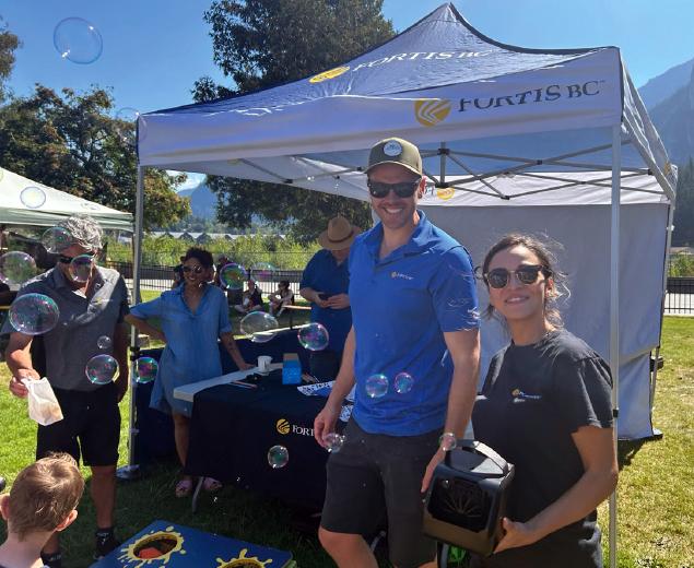 People at a FortisBC booth outdoors with bubbles floating around