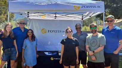 Group of people standing under a Fortis BC tent at an outdoor event