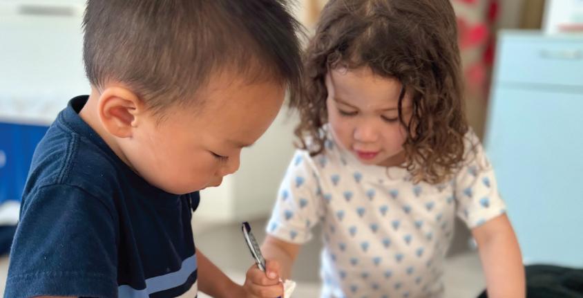 Two young children working together on writing or drawing activity