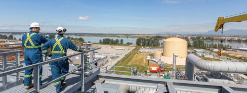 Two men stand on a platform overlooking the Tilbury LNG facility